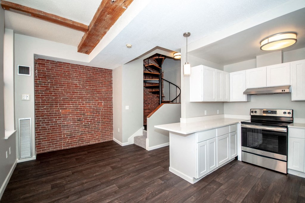 an open kitchen with a brick wall and a spiral staircase